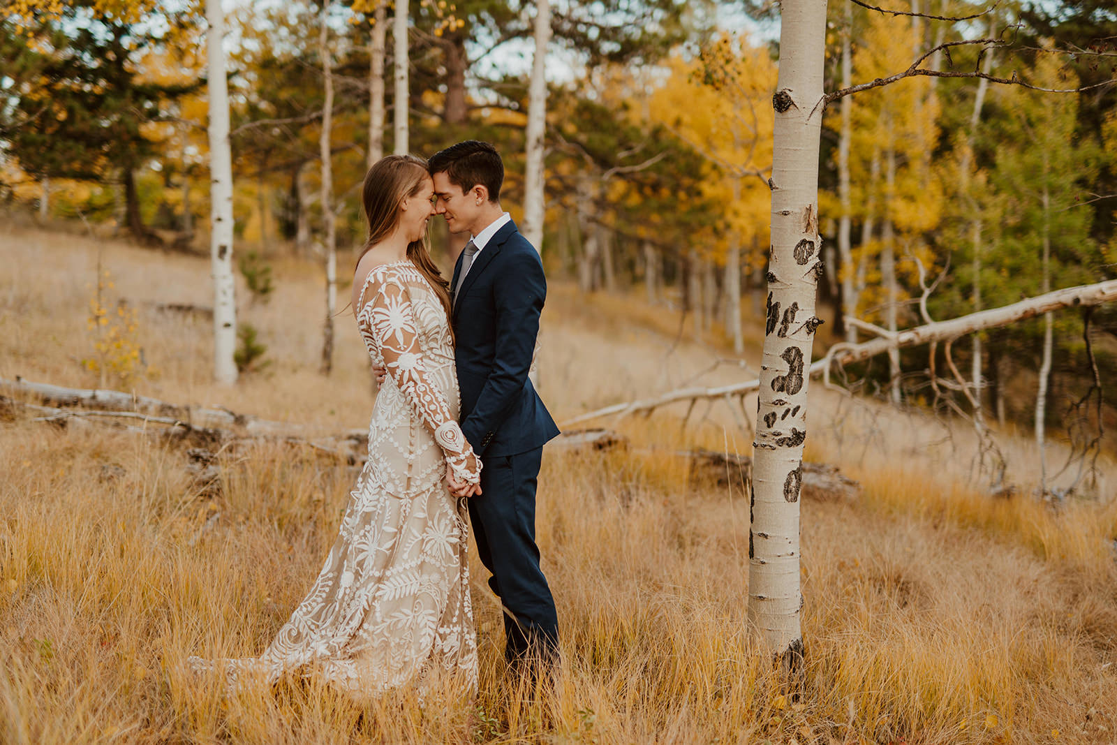 A couple embracing during their fall elopement in Colorado surrounded by golden aspen trees.