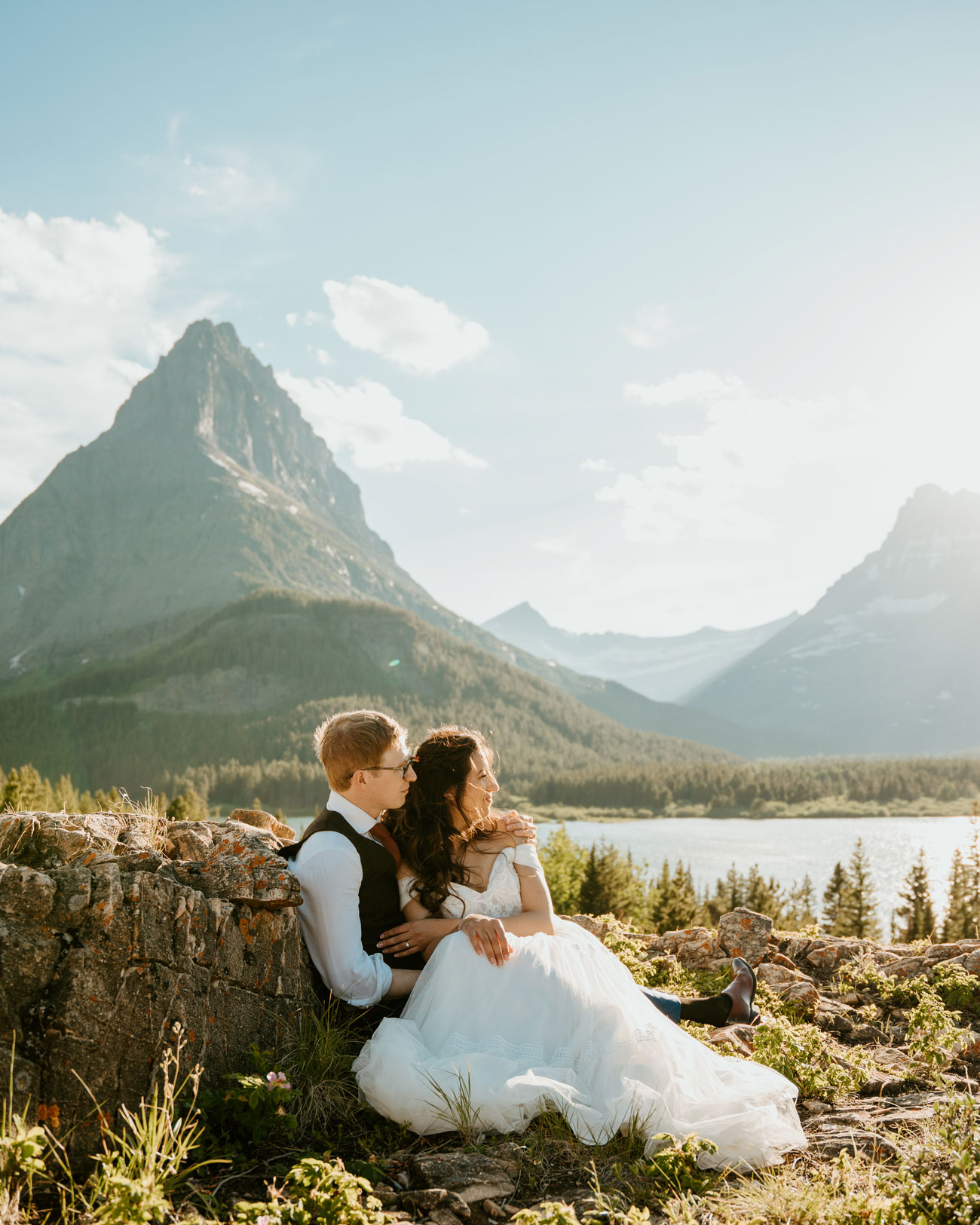 A couple sitting together and looking into the distance after their wedding in Glacier National Park.